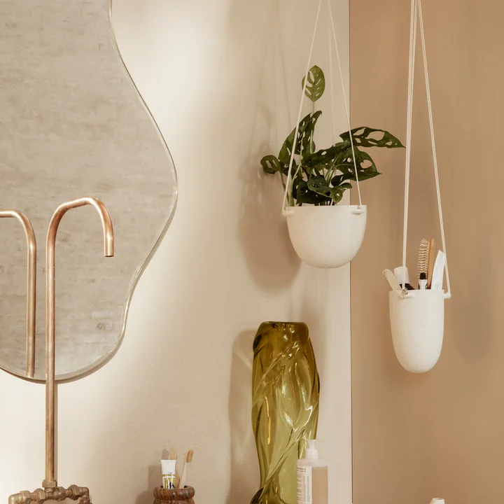 The Speckle hanging flowerpot by Ferm Living in its different sizes in the bathroom next to a mirror