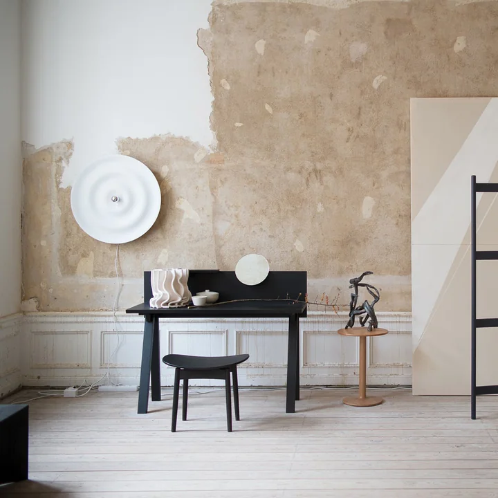 The Alma Wall and ceiling lamp from Wästberg in white in a bright studio with black desk and chair