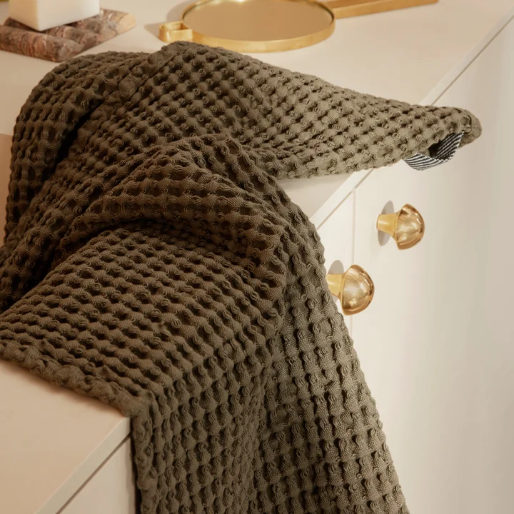The Organic bath towel from Ferm Living in olive on the washbasin cabinet in the bathroom