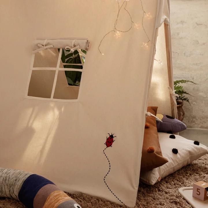 The play tent from Ferm Living with cushions and fairy lights in the children's room