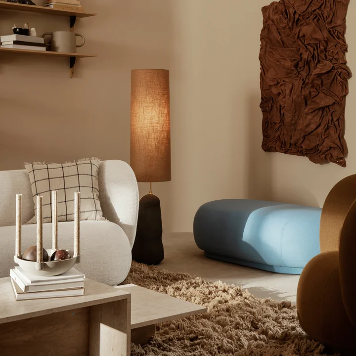The Rico sofa from Ferm Living on a brown carpet behind a travertine coffee table
