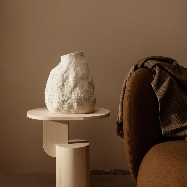The Vulca Vase from Ferm Living on a wooden side table next to a brown armchair