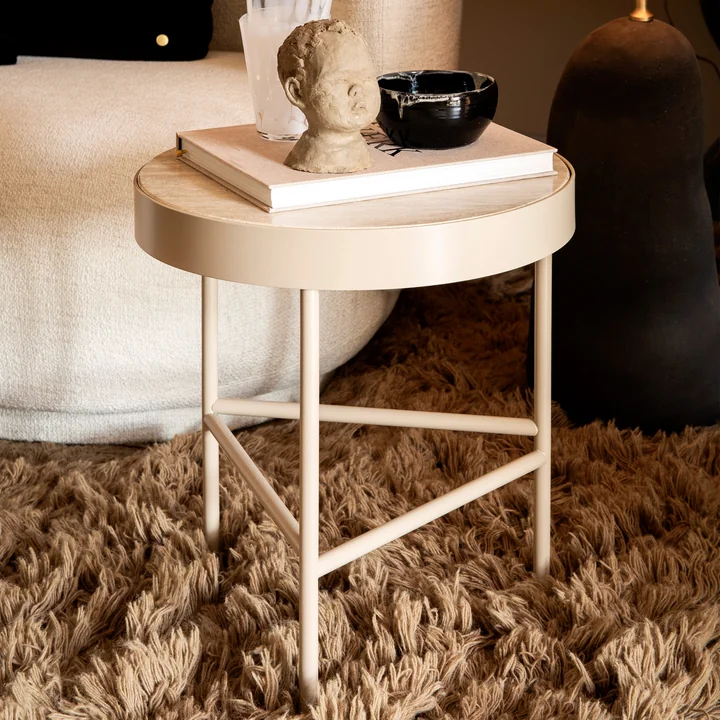 The small Travertine coffee table by Ferm Living next to a couch with books and art objects