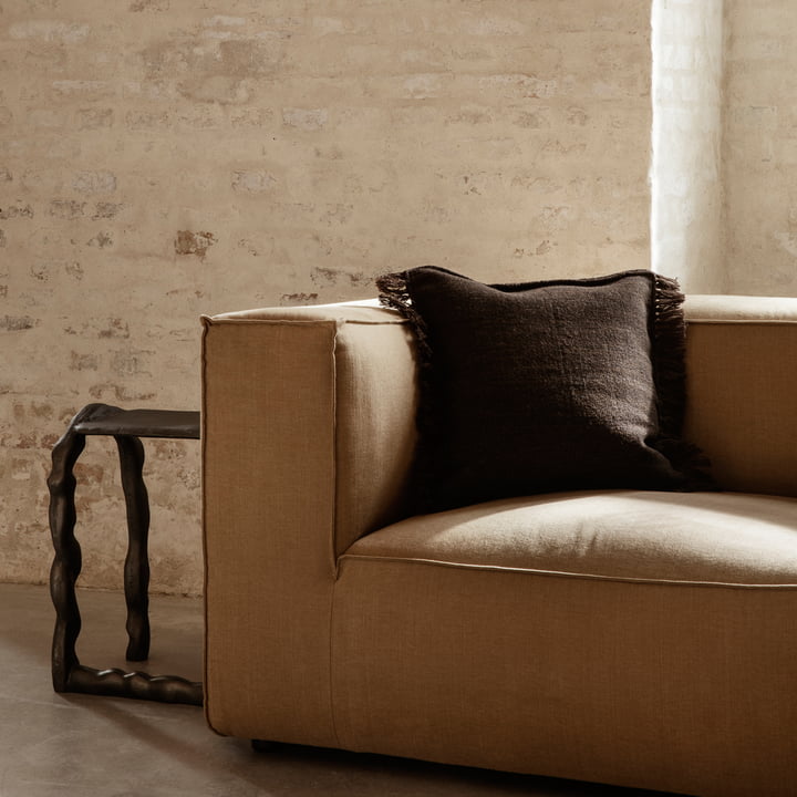 The Kelim Cushion from ferm Living in dark melange on a voluminous, light brown sofa