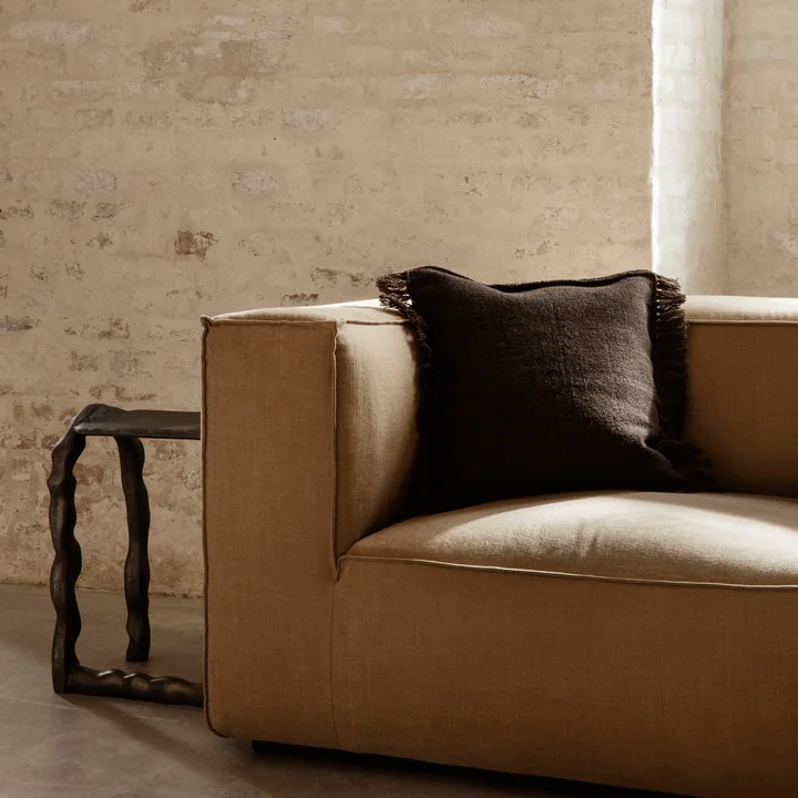 The Kelim Cushion from Ferm Living in dark melange on a voluminous, light brown sofa