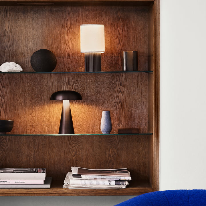 The Manhattan SC52 rechargeable table lamp from & Tradition on a wall shelf alongside other lamps and art objects