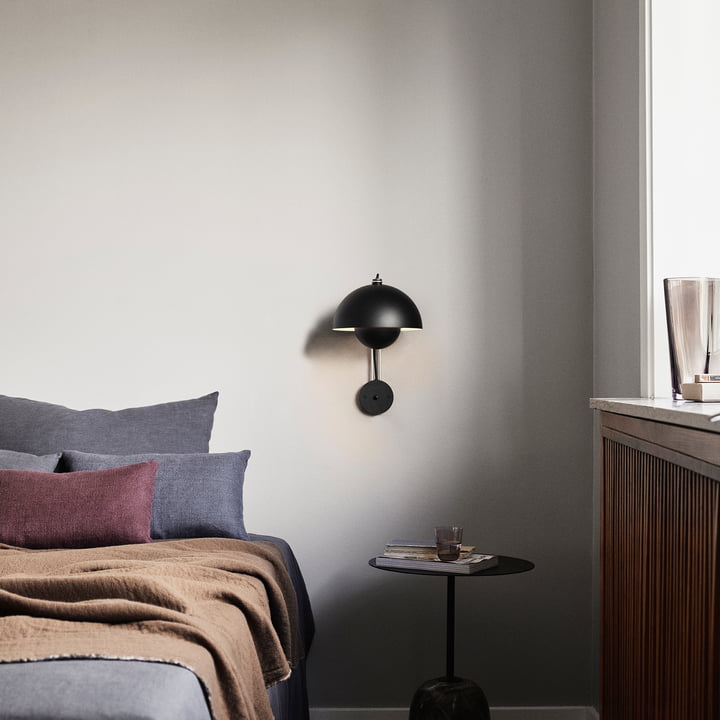 The Flowerpot wall lamp VP8 from & Tradition in black next to a bed above a nightstand