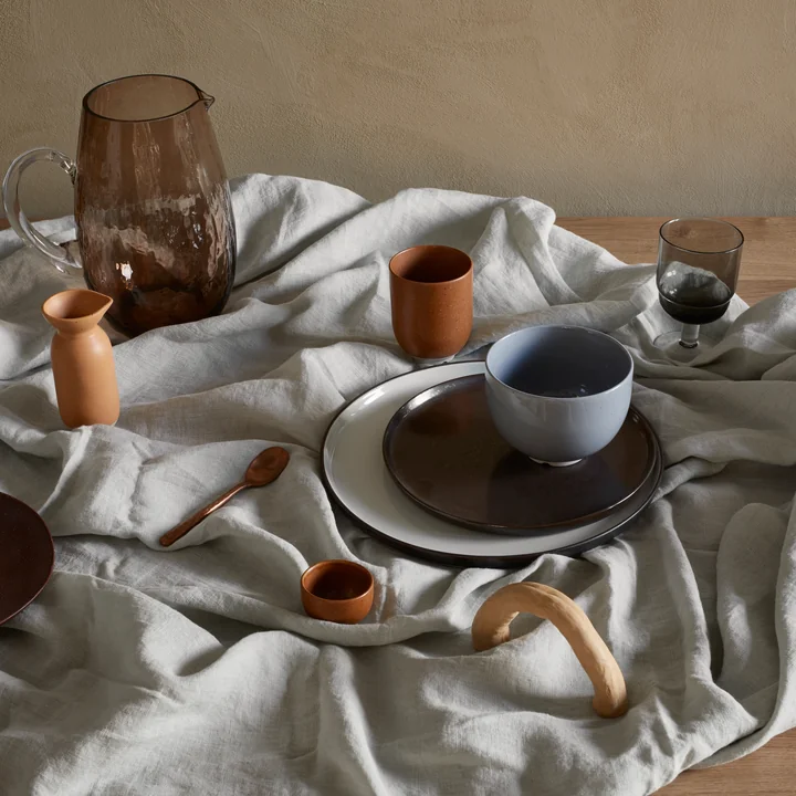 The Eli tableware from Broste Copenhagen next to glass jugs and glasses on a grey tablecloth