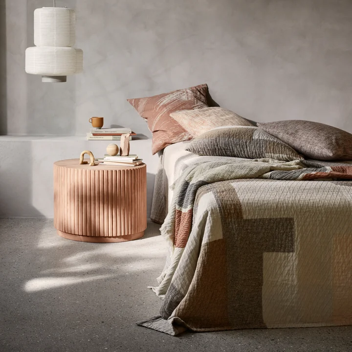 The Patch Bedspread from Broste Copenhagen in a gray bedroom on a bed next to matching Patch pillowcases
