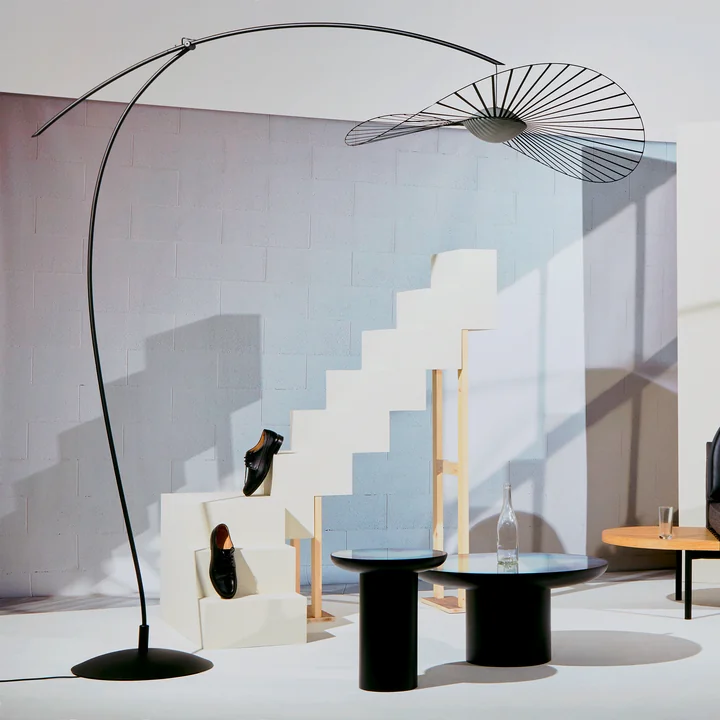 The Vertigo Nova floor lamp from Petite Friture in black in a bright living area with white stairs and black side table