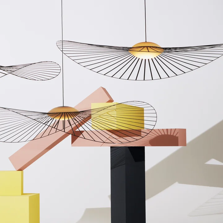 The Vertigo Nova pendant lamp from Petite Friture next to colorful art objects