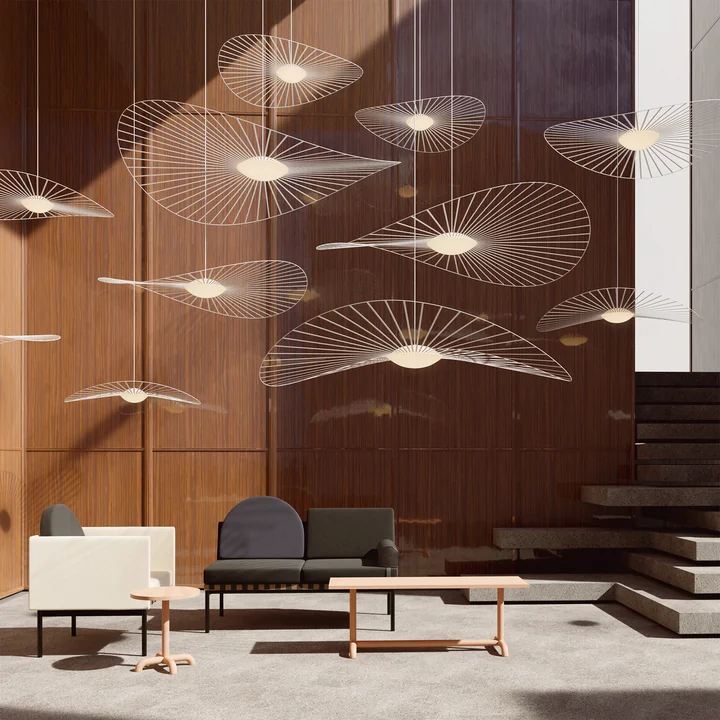 The Vertigo Nova pendant lights from Petite Friture in white in a room with high ceilings, armchairs and tables
