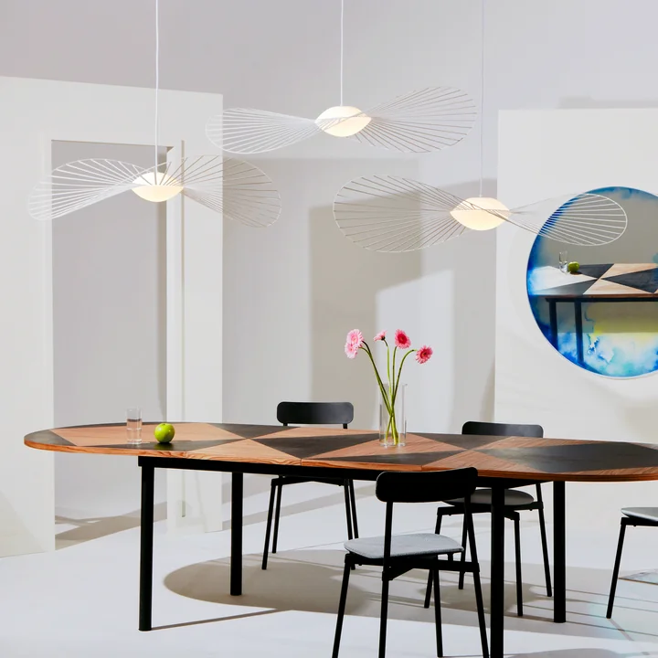 The Vertigo Nova pendant lamp from Petite Friture in the group over an oval wooden dining table with black chairs