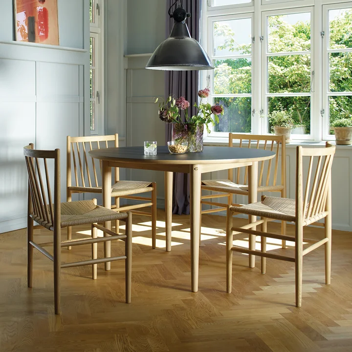 The J80 chair from FDB Møbler in oak at a light-colored dining table in a country-style room