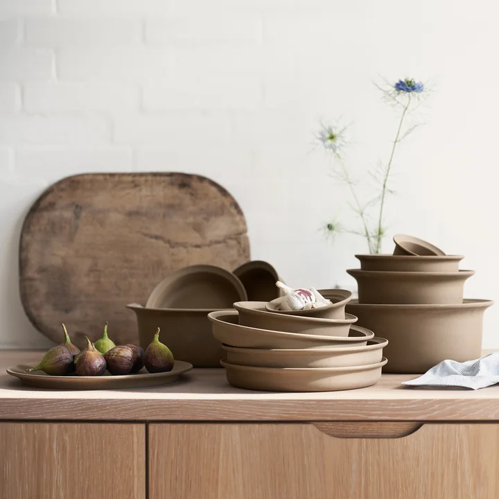 The brown tableware from the Ildpot series by FDB Møbler stacked on a wooden kitchen unit