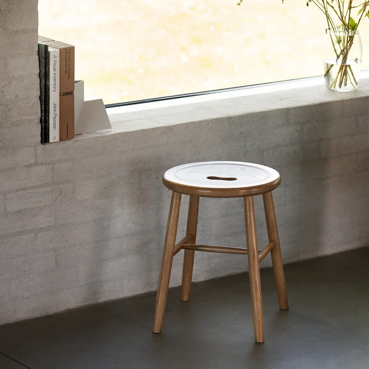 The J27 stool from FDB Møbler in natural oak in front of the window