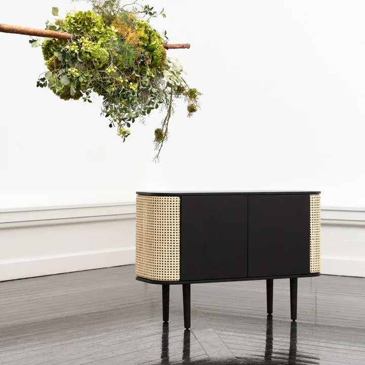 The Treasures Sideboard from Umage in black / wickerwork with a green bouquet of flowers