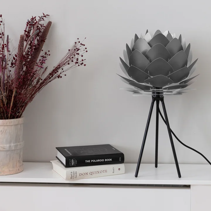 The Silvia mini lampshade from Umage in grey on a white sideboard next to books and a plant