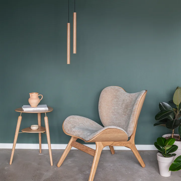 The Chimes Pendant lamp LED in oak over a lounge chair and a wooden side table, all from Umage