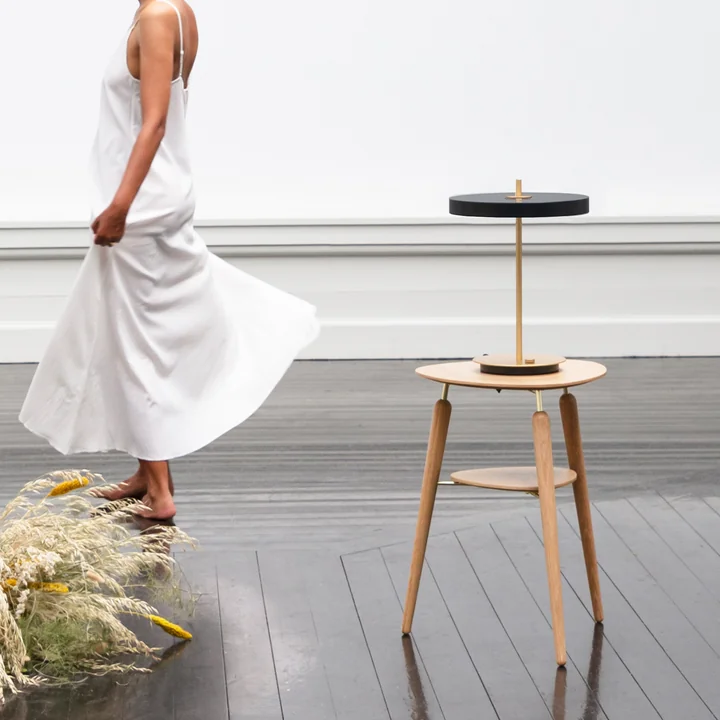 The Asteria LED table lamp from Umage in black on a wooden side table