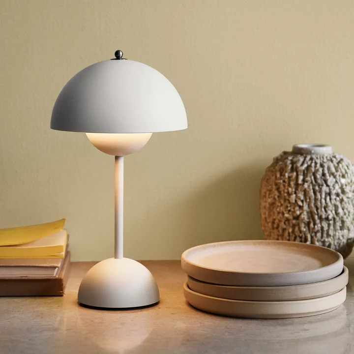 The Flowerpot battery table lamp VP9 from & Tradition next to plates, books and vases on a table