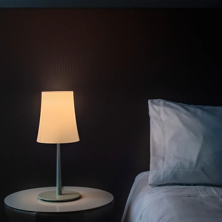 The Birdie Easy table lamp from Foscarini on a bedside table next to the bed