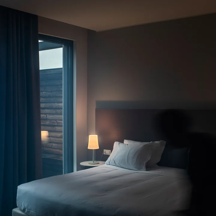 The Birdie Easy table lamp from Foscarini on the bedside table next to a bed by the window