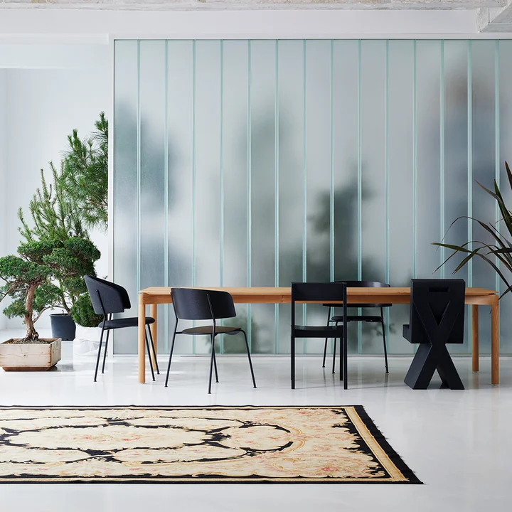 The Wagner Dining Chair from OUT Objekte unserer Tage in anthracite at a large wooden dining table next to other dark chairs