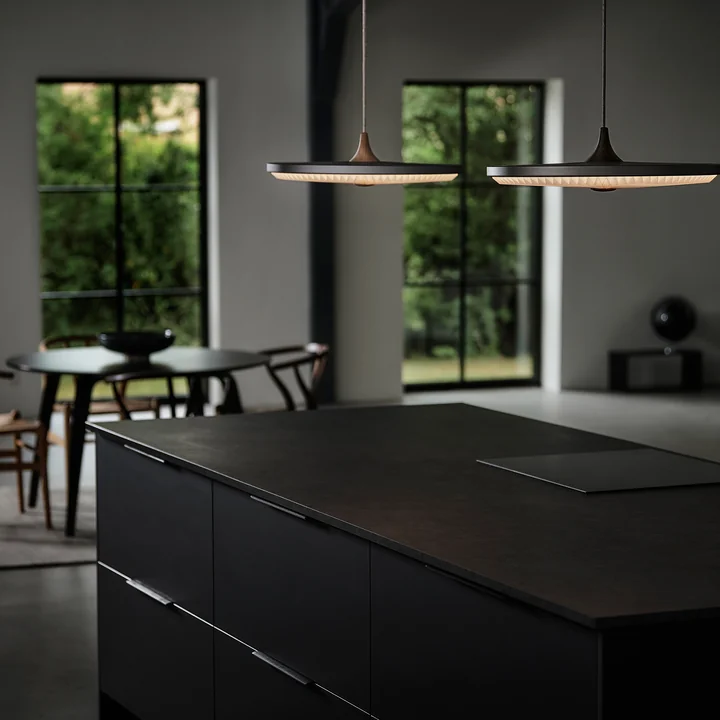 The Soleil LED pendant light from Le Klint above a dark kitchen unit