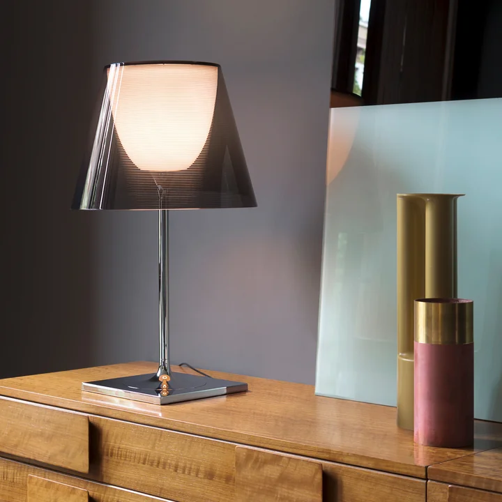 The K Tribe T2 table lamp from Flos with fumée transparent shade on a wooden chest of drawers