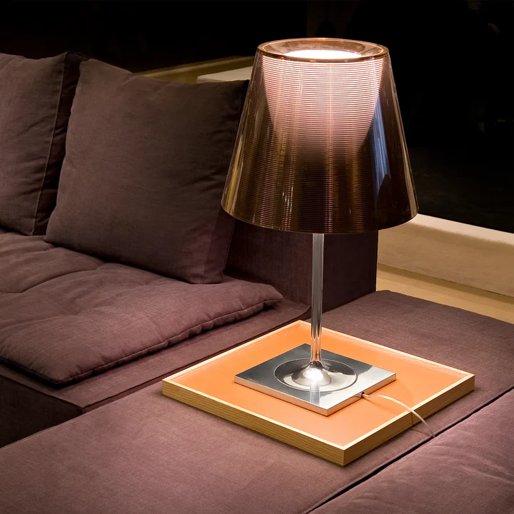 The K Tribe T2 table lamp from Flos with fumée transparent shade in a dark couch corner