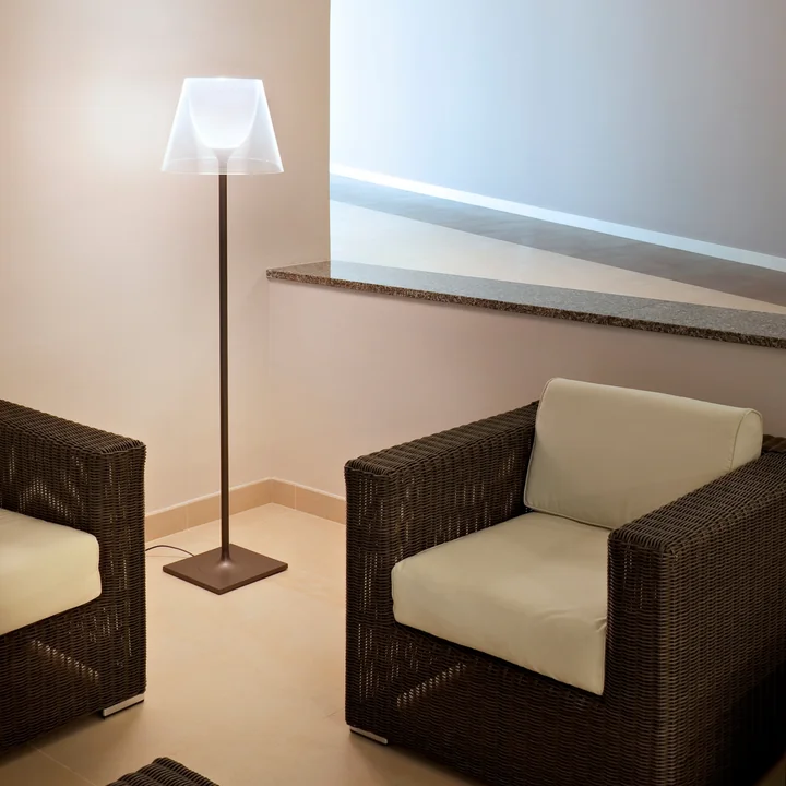 The K Tribe F2 floor lamp from Flos next to woven black and white armchairs