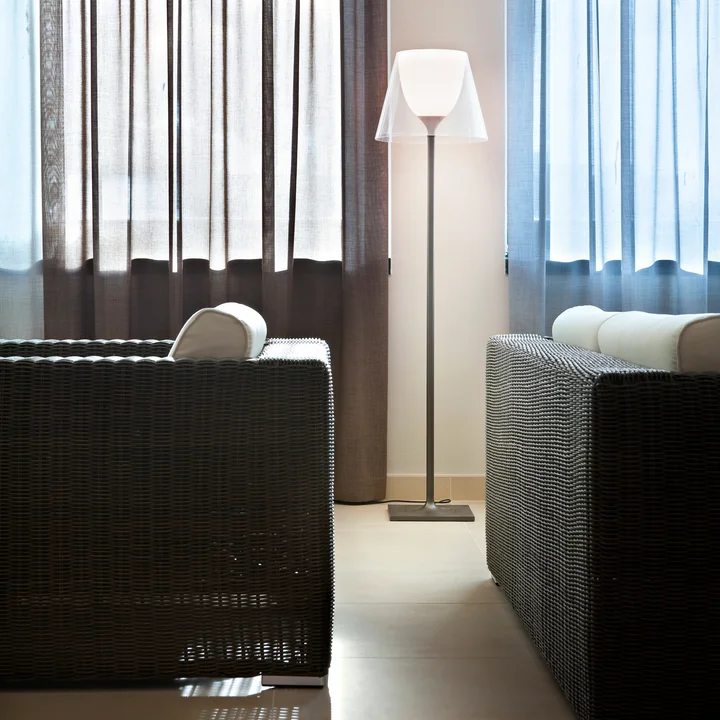 The K Tribe F2 floor lamp from Flos with transparent shade between woven black and white armchairs