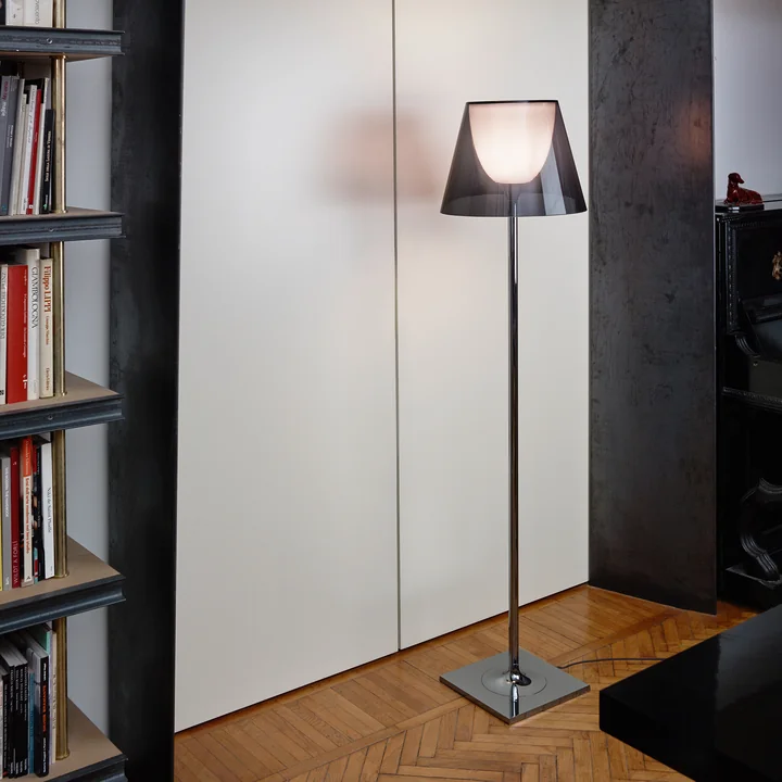 The K Tribe F2 floor lamp from Flos with fumée transparent shade next to a high bookshelf