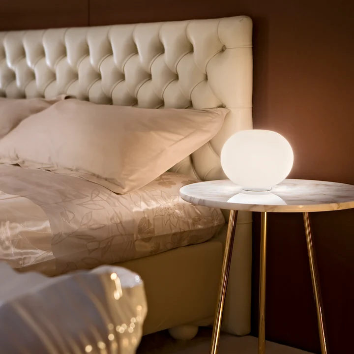 The Glo Ball Basic Zero from Flos in white on a bedside table next to the bed