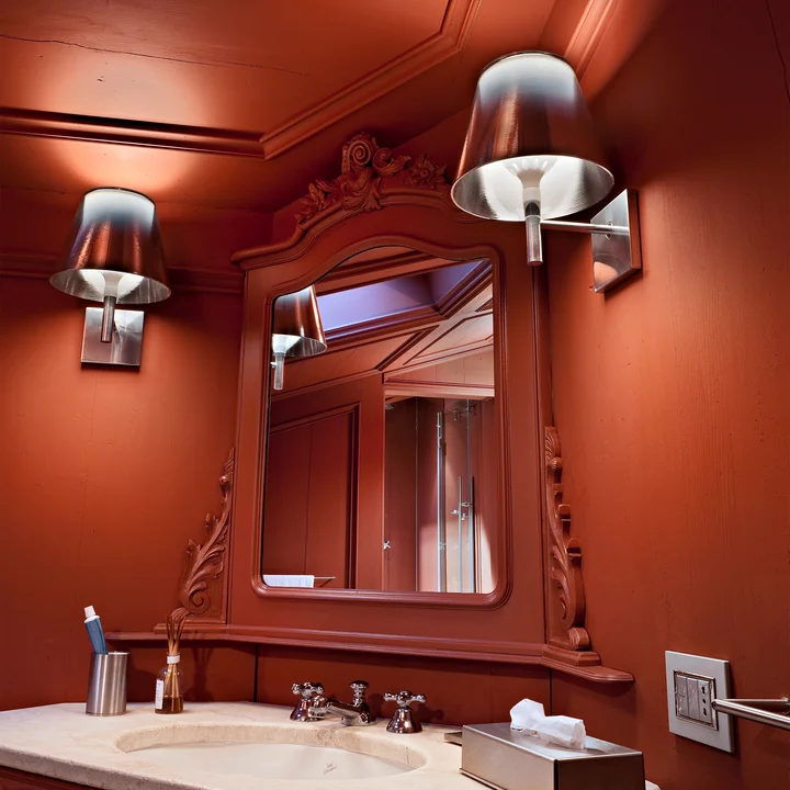The K Tribe wall lights from Flos next to the mirror in a red bathroom