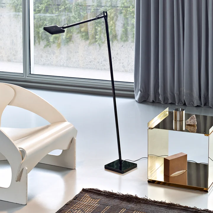 The Kelvin LED F floor lamp from Flos in black next to a white lounge chair and a golden side table