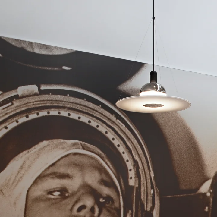 The Frisbi pendant lamp from Flos in chrome in front of a large photograph