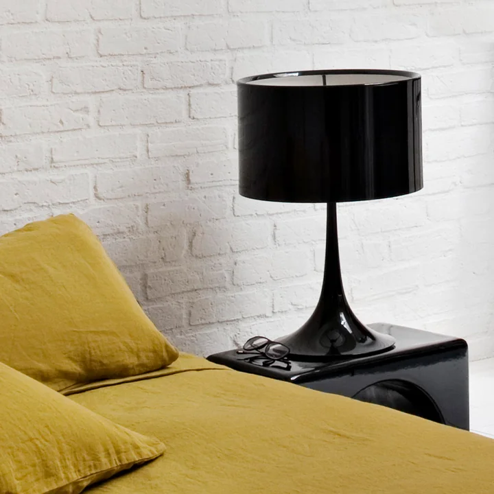 The Spun Light T2 from Flos in black on a black side table next to a yellow couch