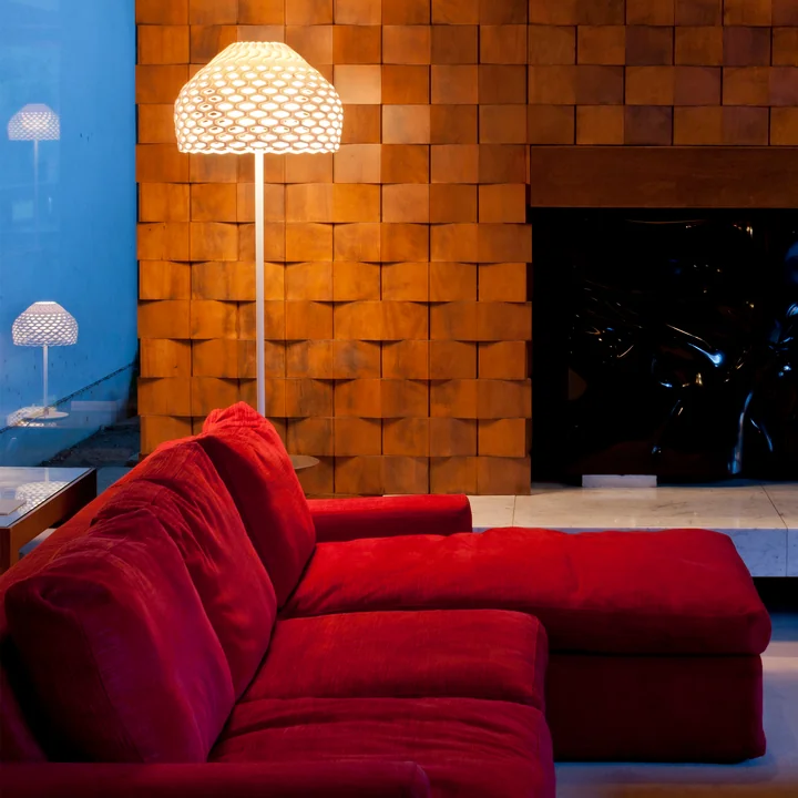 The Tatou floor lamp from Flos in white in the living area next to a red sofa