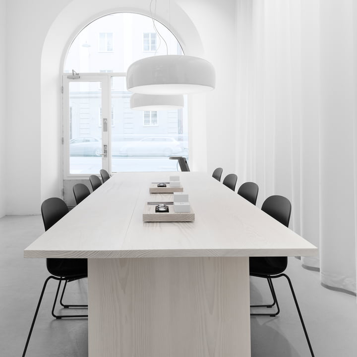 The Smithfield Pro pendant lamp from Flos in white above a light wooden table with black chairs