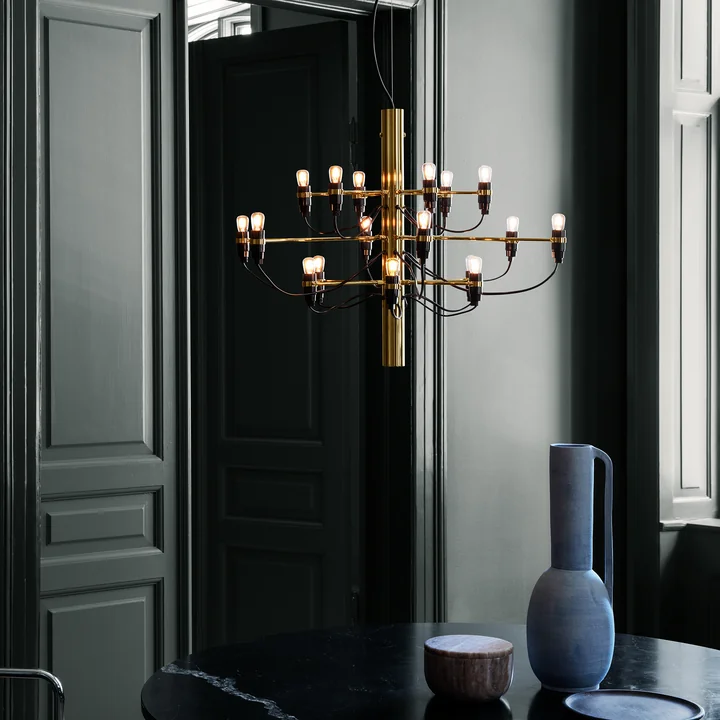 The luminous chandelier 2097/18 from Flos in brass over a black dining table