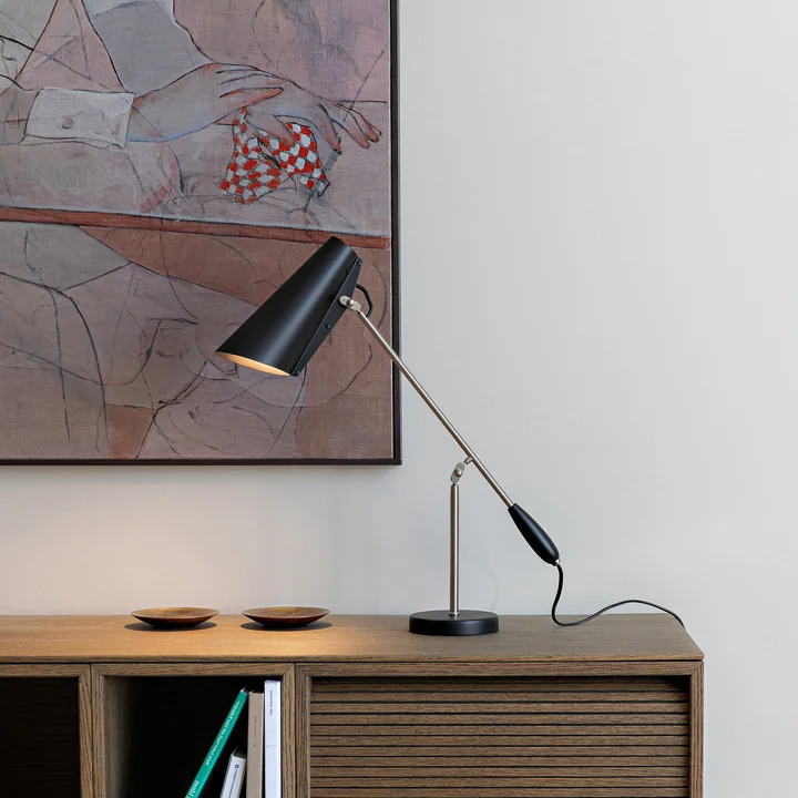 The Birdy Table lamp from Northern on a wooden dresser in front of a work of art