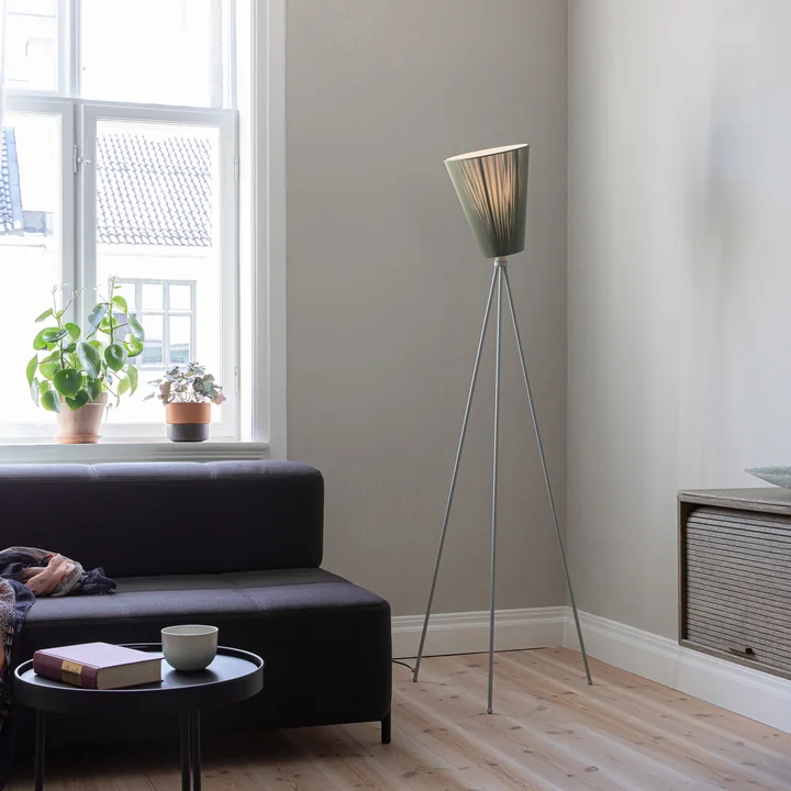 The Oslo Wood floor lamp from Northern in the living area next to a dark sofa