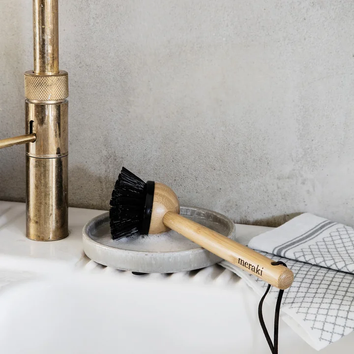 The sink brush from Meraki next to the tap on the edge of the sink