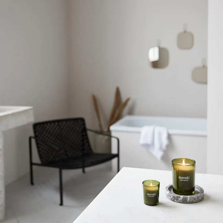 The scented candle from Meraki on a white shelf in the spacious bathroom