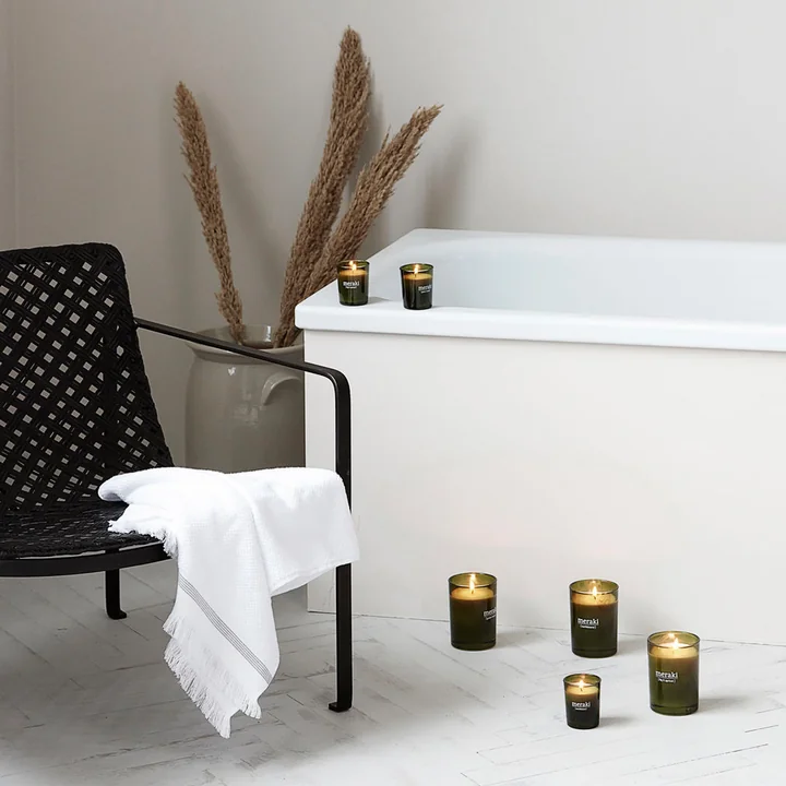 The scented candle from Meraki next to a bathtub