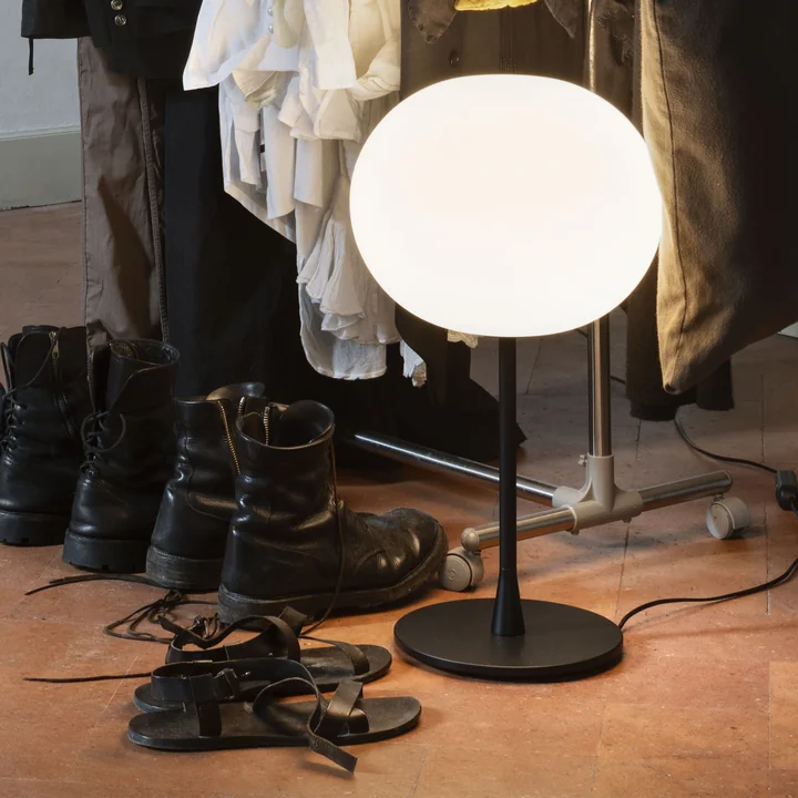 The Glo-Ball table lamp from Flos in black next to a wardrobe on the floor
