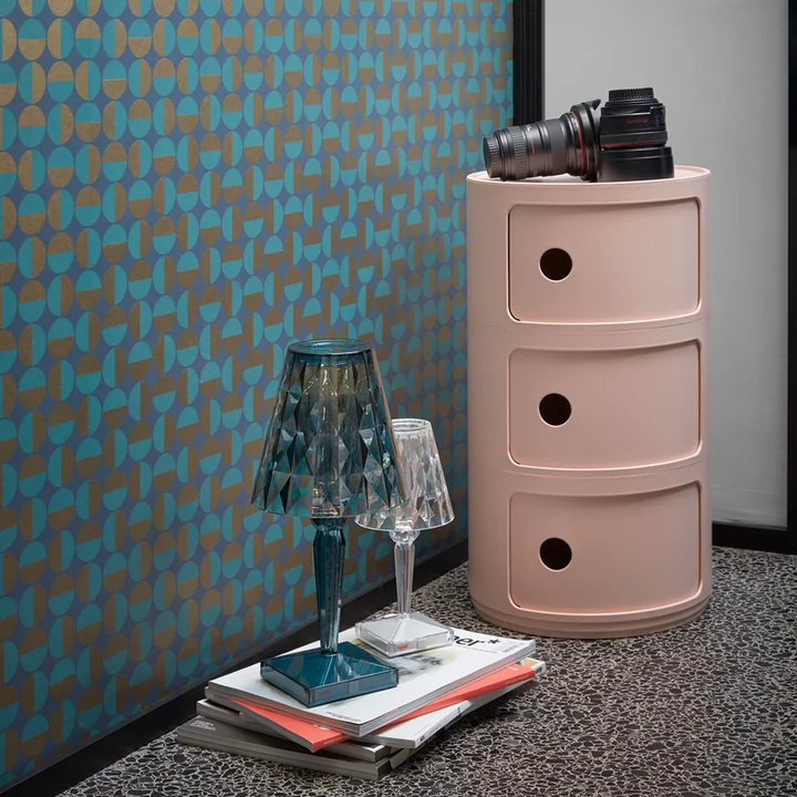 The Componibili Bio 5970 from Kartell in pink next to books and table lamps