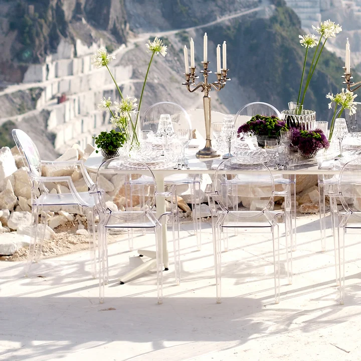 The transparent Louis Ghost Chairs from Kartell at a long table outside